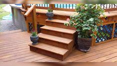 some potted plants are sitting on the wooden steps next to a fence and railing