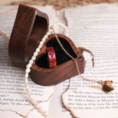 an open wooden box on top of a book with pearls and a necklace in it