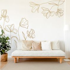 a white couch sitting in front of a wall with flowers on it