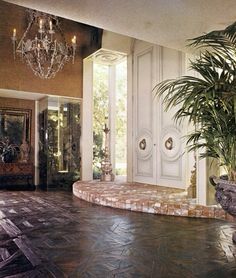 a large entry way with a potted plant and chandelier