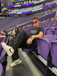 a man sitting in the middle of an empty stadium with his legs crossed and sunglasses on