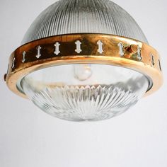 a close up of a light fixture on a white wall with gold trimmings