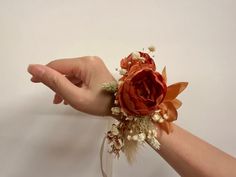 a person's hand is holding a flower arrangement in a glass vase with dried flowers