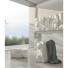 two white sculptures sitting on top of a hard wood floor next to a large window