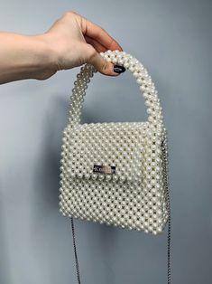 a handbag made out of pearls is being held by a woman's hand