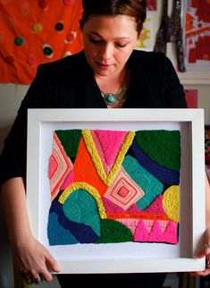 a woman holding up a framed artwork piece