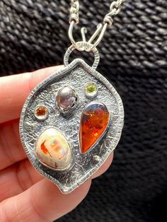 Artisan Amber with Mexican Fire Opal pendant in sterling silver  Hand-made Sterling Silver 925  Stones used: Baltic Amber, Mexican Fire Opal Purple Pearl,   Peridot, Citrine   Height - 2”, Width – 1 3/8” Unique Handcrafted One-of a-kind Design PendantEach Piece of Jewelry in my Collection is Absolutely One of a Kind!When you start wearing a piece of my jewelry you will fall in love with it more and more each day and feel that good Energy and Love that I pass into it while creating this piece of Witch Earrings, Mexican Fire Opal, Amber Gemstone, Pink Tourmaline Ring, Purple Pearl, Gift For Woman, Garnet Stone, Statement Pendant, Handcrafted Earrings