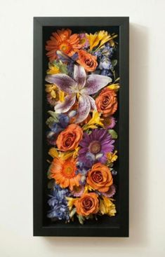 an art piece with flowers in it hanging on the wall