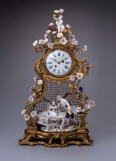 an ornate clock with figurines and flowers on it