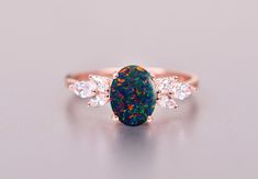 a black opal and diamond ring on a white surface, with three diamonds around it