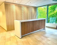 an empty reception area with large windows and wooden slats on the wall, along with tile flooring