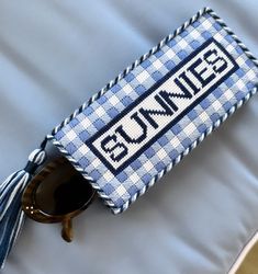 a pair of sunglasses sitting on top of a blue and white pillow with the word bennie written across it