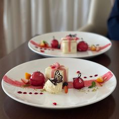 two white plates topped with desserts on top of a wooden table