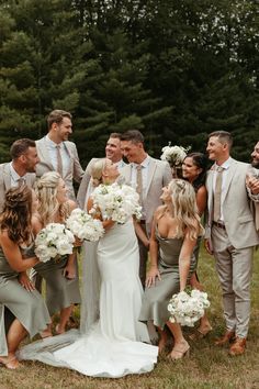 a group of people standing next to each other in front of trees and grass with white flowers