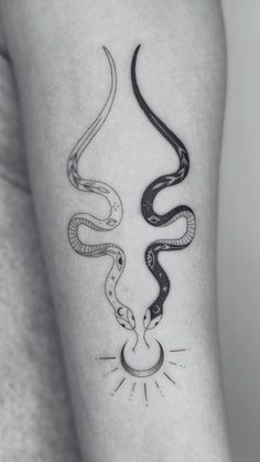 a woman's arm with two snakes on it, one is black and the other is