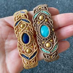 two gold and blue beaded bracelets in the palm of someone's hand