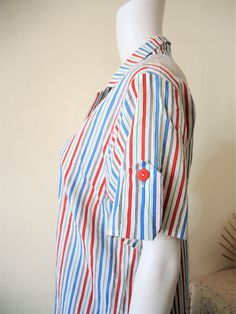 Beautiful Finnish True Vintage blouse from the 1980s. Made from a comfortable light flowy cotton fabric with a colorful stripe pattern. Straight, generous cut. Short lapel collar, wide short sleeves with decorative cuff adjusters, red buttons. Made in Finland! BRAND: Pia & Paula ERA: 1980s COLOR: White, red, blue,green, black FABRIC: 100% cotton SIZE: Vintage size 36, US 8, UK 10, fits best a size M (or S for a more oversized fit) - please check measurements below for reference MEASUREMENTS: Spring Short Sleeve Blouse With Vertical Stripes, Spring Blouse With Vertical Stripes And Short Sleeves, Daywear Blouse With Striped Collar And Short Sleeves, Multicolor Short Sleeve Tops With Striped Collar, Striped Short Sleeve Blouse For Daywear, Multicolor Short Sleeve Blouse For Daywear, Summer Short Sleeve Blouse With Striped Collar, Short Sleeve Top With Striped Collar For Daywear, Multicolor Short Sleeve Top With Striped Collar