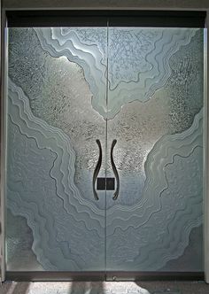 a glass door with an artistic design in the center and two handles on each side