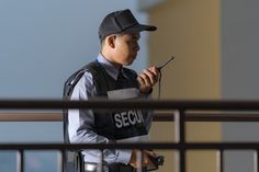 a security officer holding a cell phone and looking at the screen while standing in front of a building