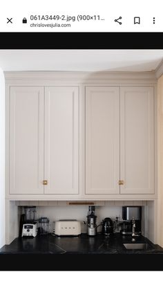 a kitchen with white cupboards and black counter tops in front of a wall mounted microwave