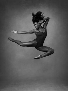 a black and white photo of a woman jumping in the air