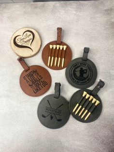 four different golf tags are shown on a white surface with black and gold trimmings