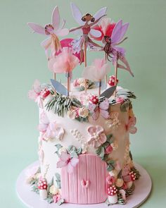 a cake decorated with pink flowers and fairy tinker wings on a white platter