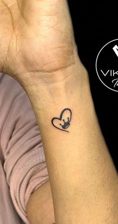 a woman's wrist with a small heart tattoo on the left side of her arm