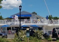 a white building with blue umbrellas and people on the balcony