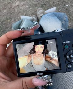 a person holding up a camera with a girl on it's screen in their hand