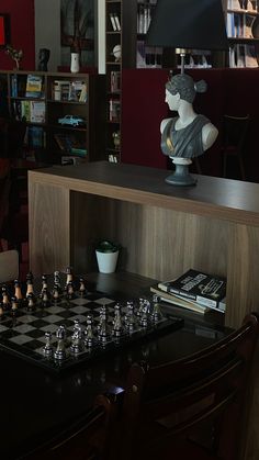 the chess board is set up in front of a busturine and bookshelf