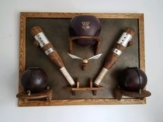 an assortment of helmets and knives on display in a wooden frame with leather straps around them