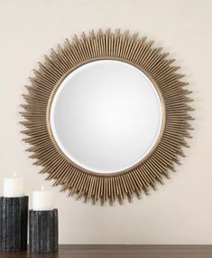 a round mirror sitting on top of a wooden table next to two black vases