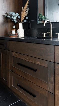 a bathroom vanity with black counter tops and wooden cabinetry, along with a plant in the corner