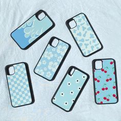 four cell phone cases sitting on top of a white sheet with cherries and flowers