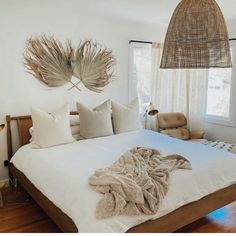 a bed with white sheets and pillows in a bedroom next to a lamp hanging from the ceiling