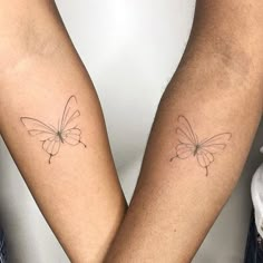 two people with tattoos on their arms holding each other's hands and one has a butterfly tattoo on it