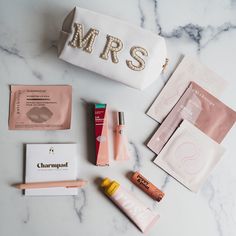 personal care items laid out on a marble counter top with the word mrs spelled in gold