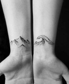 two hands with mountains on their wrist tattooing it's both small and large