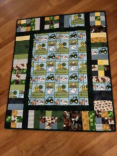 a quilted table topper with farm animals and tractors on it, sitting on a wooden floor