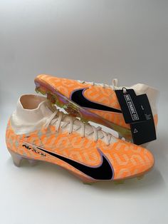 a pair of orange and white soccer cleats sitting on top of a table