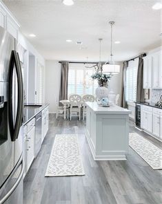 a large kitchen with white cabinets and gray flooring is pictured in this image, the center island has an area rug on it