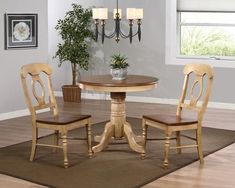 a dining room table with two chairs and a potted plant in the corner next to it