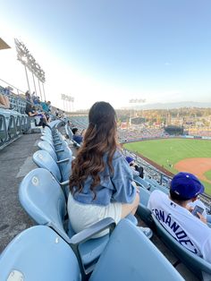 two people are sitting in the stands at a baseball game, looking out into the field