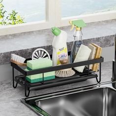 a kitchen sink with cleaning supplies on the tray and in front of it is a window