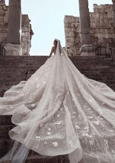 a woman in a wedding dress standing on some steps with her veil blowing in the wind