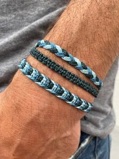 a man wearing two different colored bracelets on his arm, one is blue and the other is gray