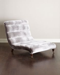 a white chaise lounge chair sitting on top of a hard wood floor next to a window