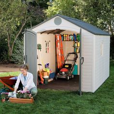 a woman kneeling down in front of a shed with gardening supplies on the ground next to it