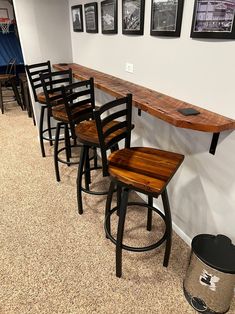 a row of bar stools sitting next to a wall with pictures hanging on it